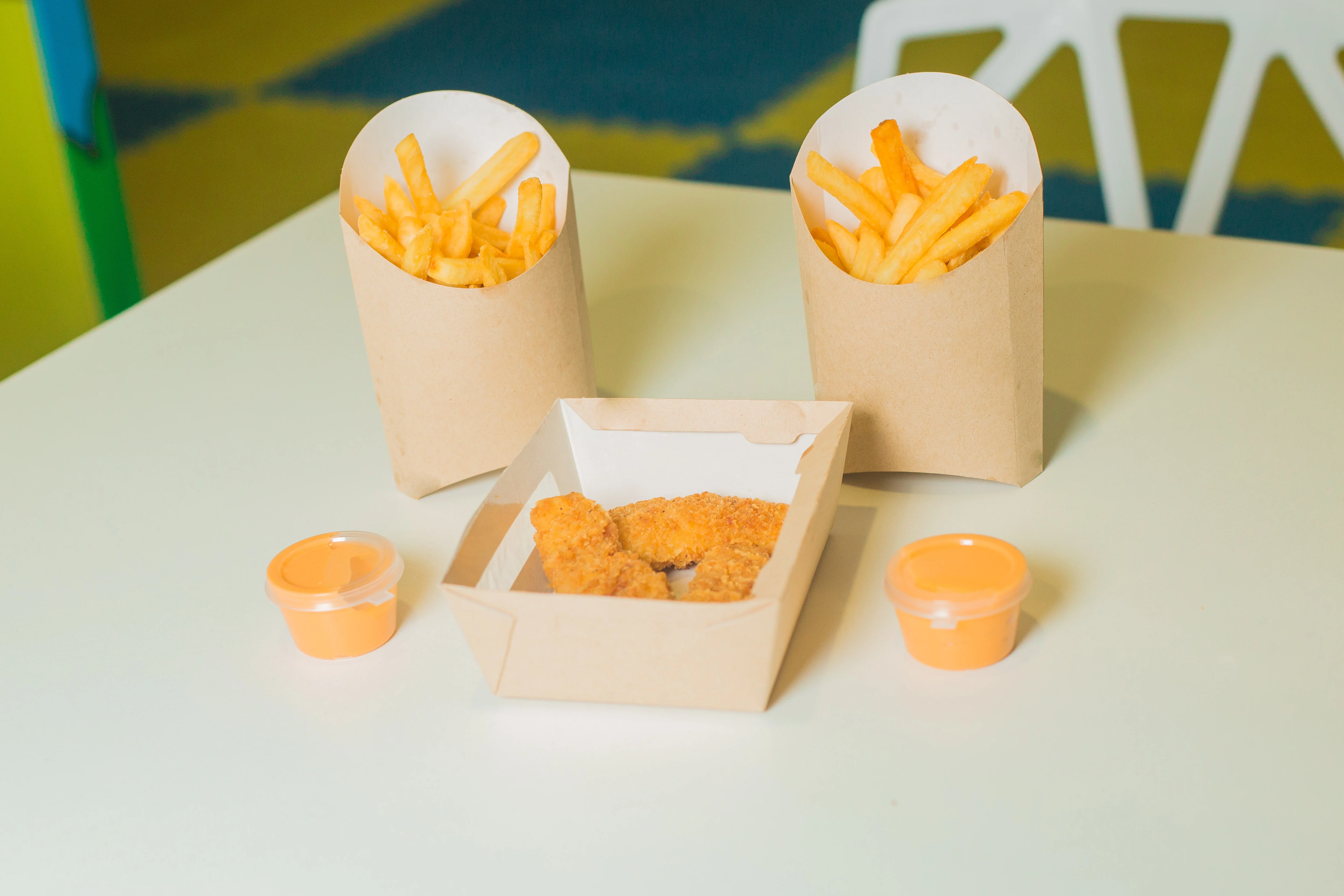 Картофель фри, куриные наггетсы и соусы на столе в детском кафе